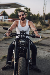 Fototapeta na wymiar Smiling biker in sunglasses on his motorcycle