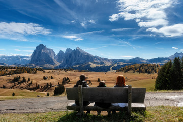 Family sitting on bench with dolomites landscape