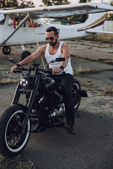 Fototapeta na wymiar Handsome biker in white t-shirt going to ride a motorcycle