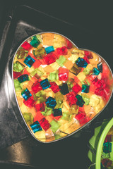 Jelly cake in the form of a heart with multi-colored cubes in the middle. The cake is being prepared.