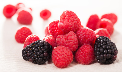 handful of fresh raspberry and blackberry berries on white background