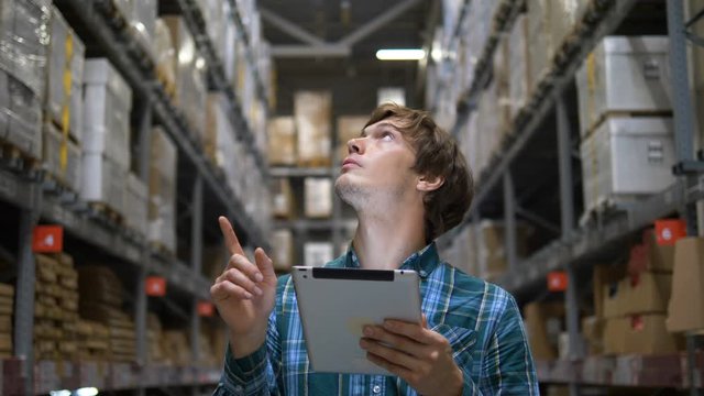 man looks at shelves and enters goods information to tablet