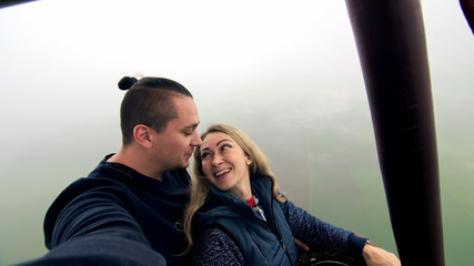 Adventure love couple on hot air balloon watermelon. Man and woman kiss hug love each other. Burner directing flame into envelope. Happy people.