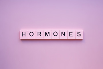 Hormones word wooden cubes on a pink background - obrazy, fototapety, plakaty