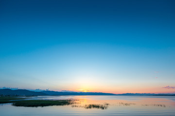 Fototapeta na wymiar Calm Lake Sevan in Armenia in the rays of the rising sun from behind the mountains