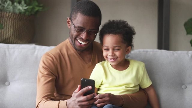 African father spend time with son having fun using smartphone