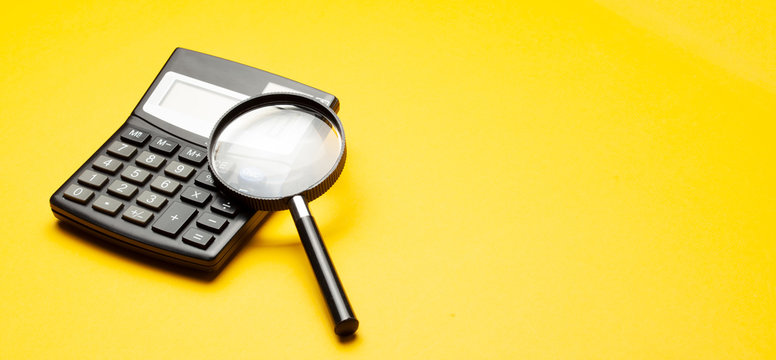 Calculator and magnifying glass on yellow background - Powered by Adobe