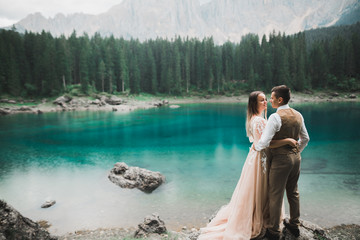 Romantic wedding moment, couple of newlyweds smiling portrait, bride and groom hugging near a beautiful lake in the mountains