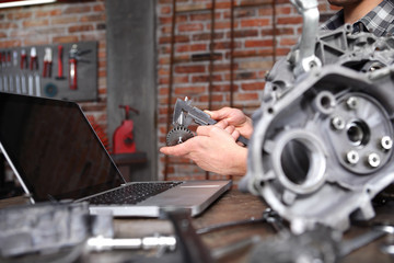 hands man work with caliper measure the motor gear, study on the computer and search in internet...