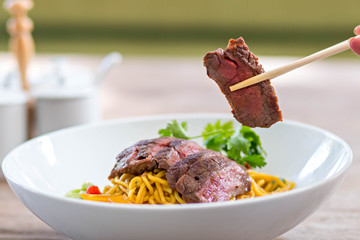chopstick pick up beef from noodle bowl