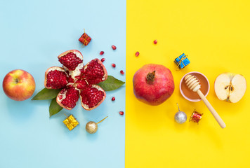 Concept Rosh Hashanah postcard with copy space ; apples, pomegranates and honey on blue and yellow background