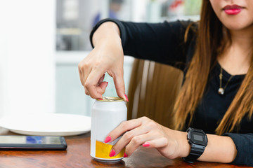 Woman's hand opening can of drink in blur background.