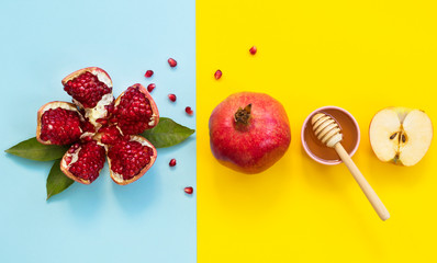 Concept Rosh Hashanah postcard with copy space ; apples, pomegranates and honey on blue and yellow background