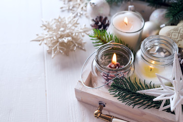 Rustic style with candles and christmas decorations on white wooden background, copy space