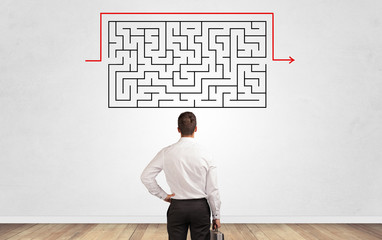 Businessman in doubt looking to a maze and searching the way out