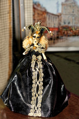 Doll of young Halloween witch in a black evening dress with dark make-up on her face and a spreading hat with a cocked hat on her head.