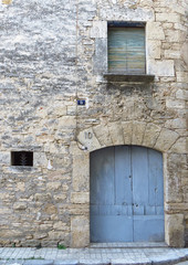 Fototapeta na wymiar Light blue wooden door in a stone facade. Small window Elegant entrance Rustic