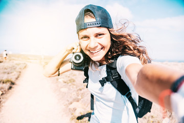 Fototapeta na wymiar Beautiful slender young girl in a baseball cap takes a selfie during summer vacation, blogger lifestyle concept
