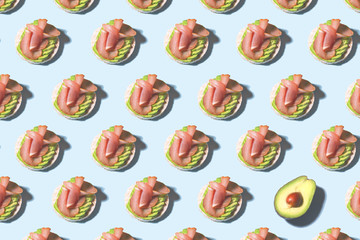 Avocado toast with ham and avocado slice pattern on bright blue background. Food pattern with sunlight. Healthy food minimal concept