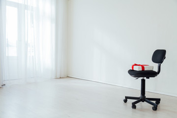 black office chair with a gift in an empty white office