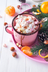 Cups of hot chocolate with marshmallows, mandarin, fir tree branches and nuts on white wooden background