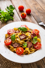 Tagliatelle with sausages on wooden table