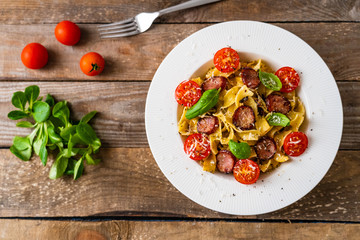 Tagliatelle with sausages on wooden table