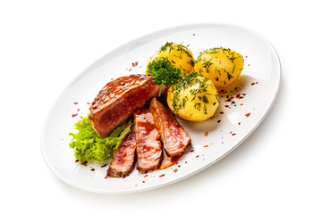 Grilled steak, boiled potatoes and vegetable salad on white background