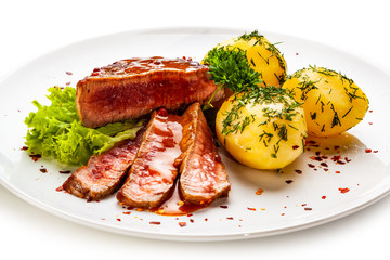 Grilled steak, boiled potatoes and vegetable salad on white background
