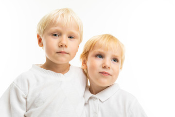 Little boys brothers with short light and red hair, blue eyes, cute appearance, in white jacket, light blue pants, stand and pose beautifully on camera