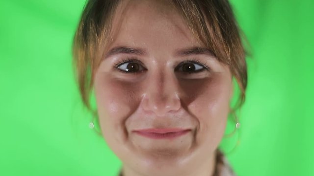 Portrait of young woman crossing her eyes on green background.