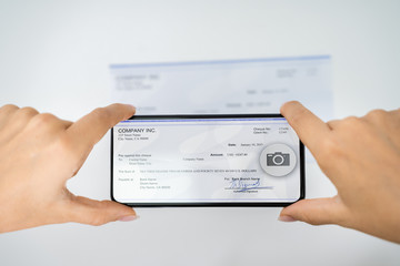 Woman Taking Photo Of Cheque To Make Remote Deposit