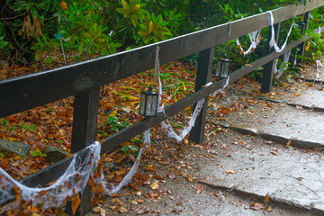 White spider Web and lantern on wooden bridge in autumn forest on Halloween holiday.