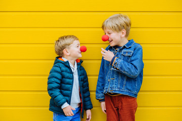 Red Nose Day Concept. Happy little brothers wearing red clown noses having fun together on sunny...