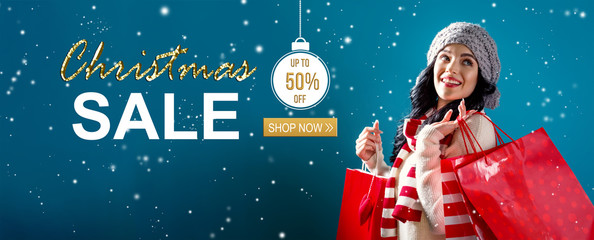 Christmas sale message with young woman holding shopping bags