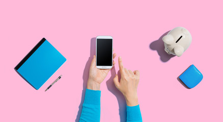Obraz na płótnie Canvas Person using a smartphone with a piggy bank