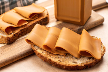 Closeup detailed food photography shot of norwegian brown cheese/brunost on rustic toasted bread...