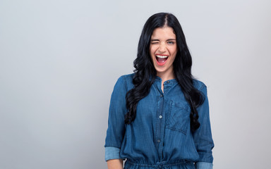 Young woman winking on a gray background