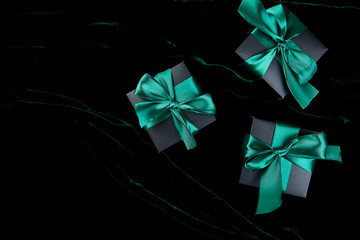 Luxury black gift boxes with green ribbon on shine velvet background. Christmas, birthday party...