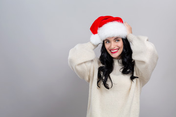 Happy woman with a Santa hat on a gray background