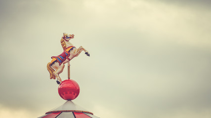Horse on the top of a carousel in a park. Traditional merry-go-round carousel horse