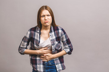 Young beautiful woman having abdominal pain isolated on grey background.