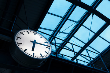 public indoor clock and skyroof in train station at twilight, clock show time at rush hour for passengers or commuters