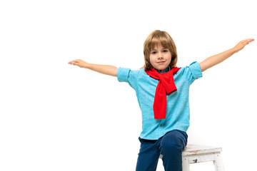 Little caucasian boy sits on a chair with red sweatshot around his neck represents the plane isolated on white background