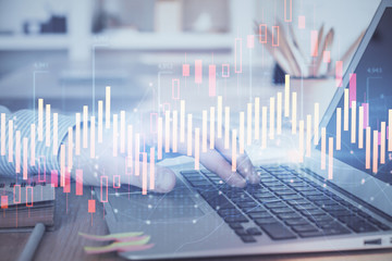 Double exposure of businessman's hands with laptop and stock market graph background. Concept of research and trading.