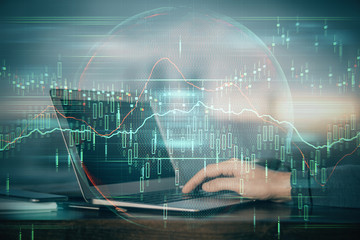 Double exposure of businessman's hands with laptop and stock market graph background. Concept of research and trading.