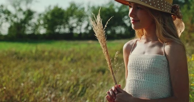 Closeup portrait beautiful preteen girl in straw hat is in the field at Sunny Day. Child smiling at camera. Slow motion