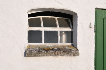 milk churn behind window of old cottage