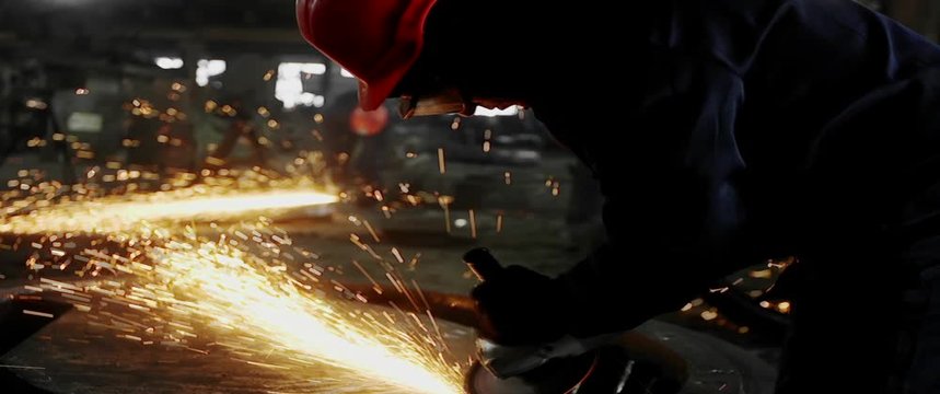Male hand cuts off pieces of water pipe with angle grinder. Cutting of a steel with splashes of sparks at construction site. Sparks during cutting of metal angle grinder