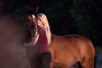 Frau kuschelt mit Pony vor dunklem Hintergrund